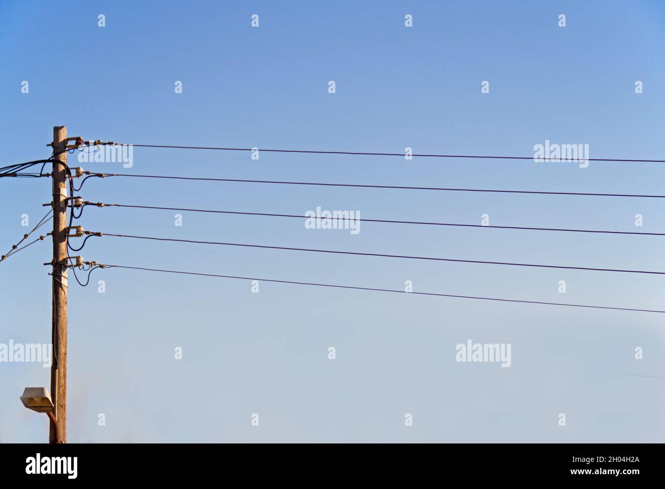 Fünf elektrische Drähte in Form eines musikalischen Stabes stellen einen klaren blauen Himmel dar Stockfoto