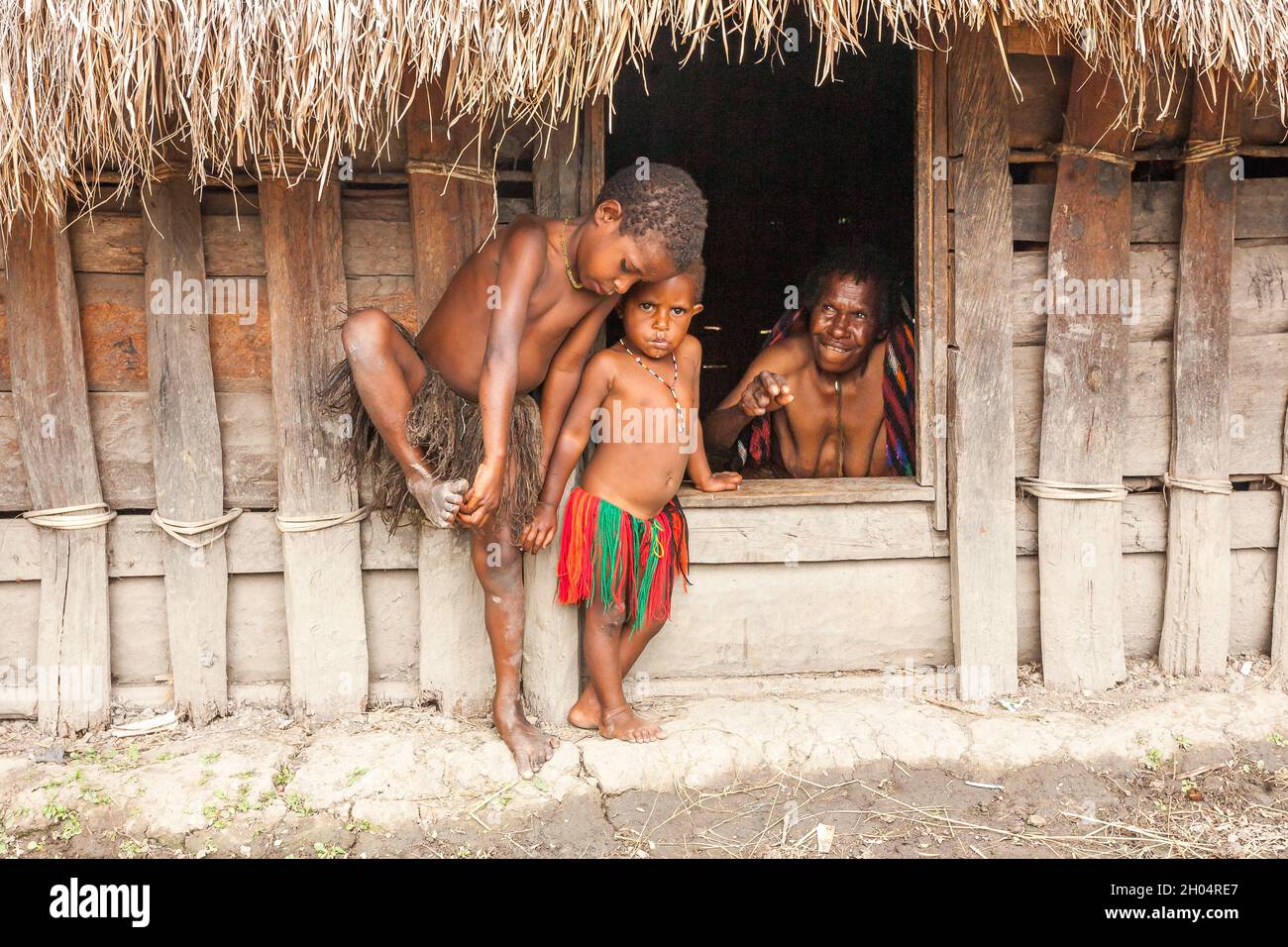 Wamena, Indonesien - 9. Januar 2010: Kinder des Dani-Stammes stehen in der Nähe von Strohhäusern, Papua-Neuguinea. Stockfoto
