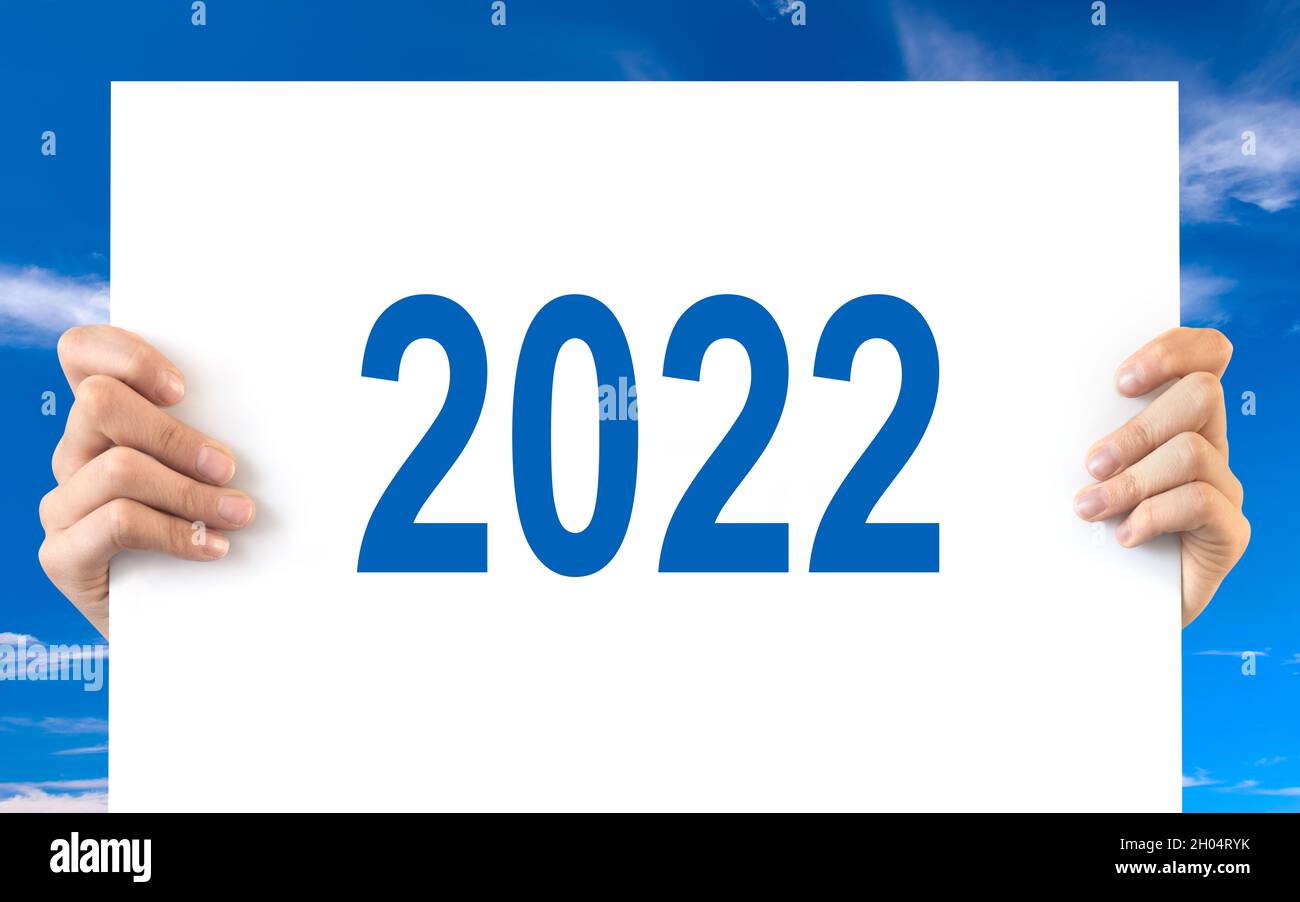 Hände mit einem weißen Brett mit 2022, blauem Himmel Hintergrund Stockfoto