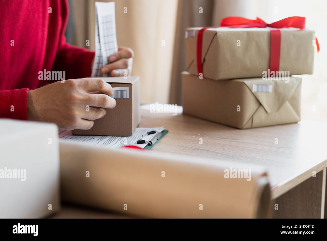 Business Start up KMU-Konzept. Aufstrebender Unternehmer, Kleinunternehmer klebt Barcodes auf Pakete, arbeitet von zu Hause aus, Verpackung und Lieferung von Waren Stockfoto