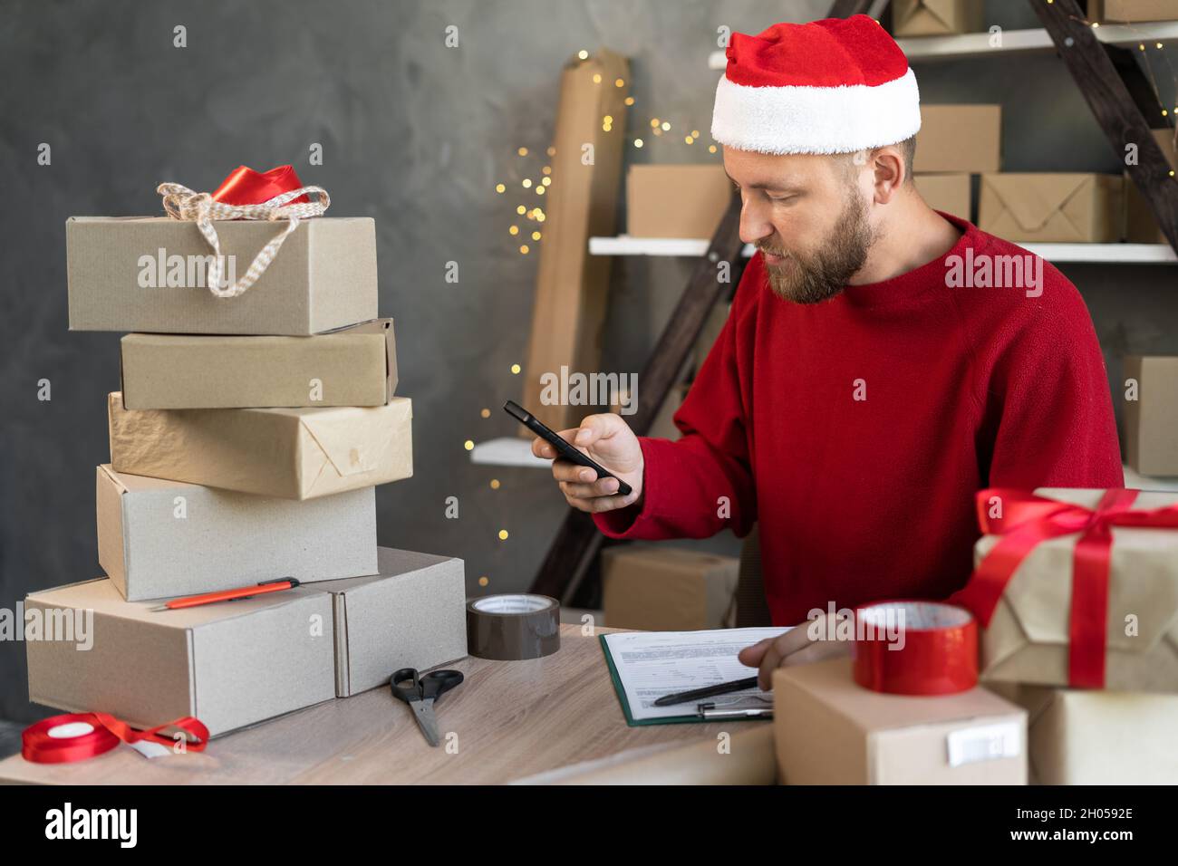 Kleinunternehmer Unternehmer arbeitet im Neujahrsheimbüro mit Boxen macht ein Foto auf dem Telefon mit Barcodes für Kunden. Online-Shop Stockfoto