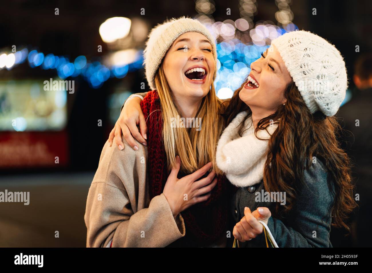 Fröhliche Frauen, die zu Weihnachten draußen in der Stadt reden und lachen. Das Konzept der glücklichen Kaufleute Stockfoto