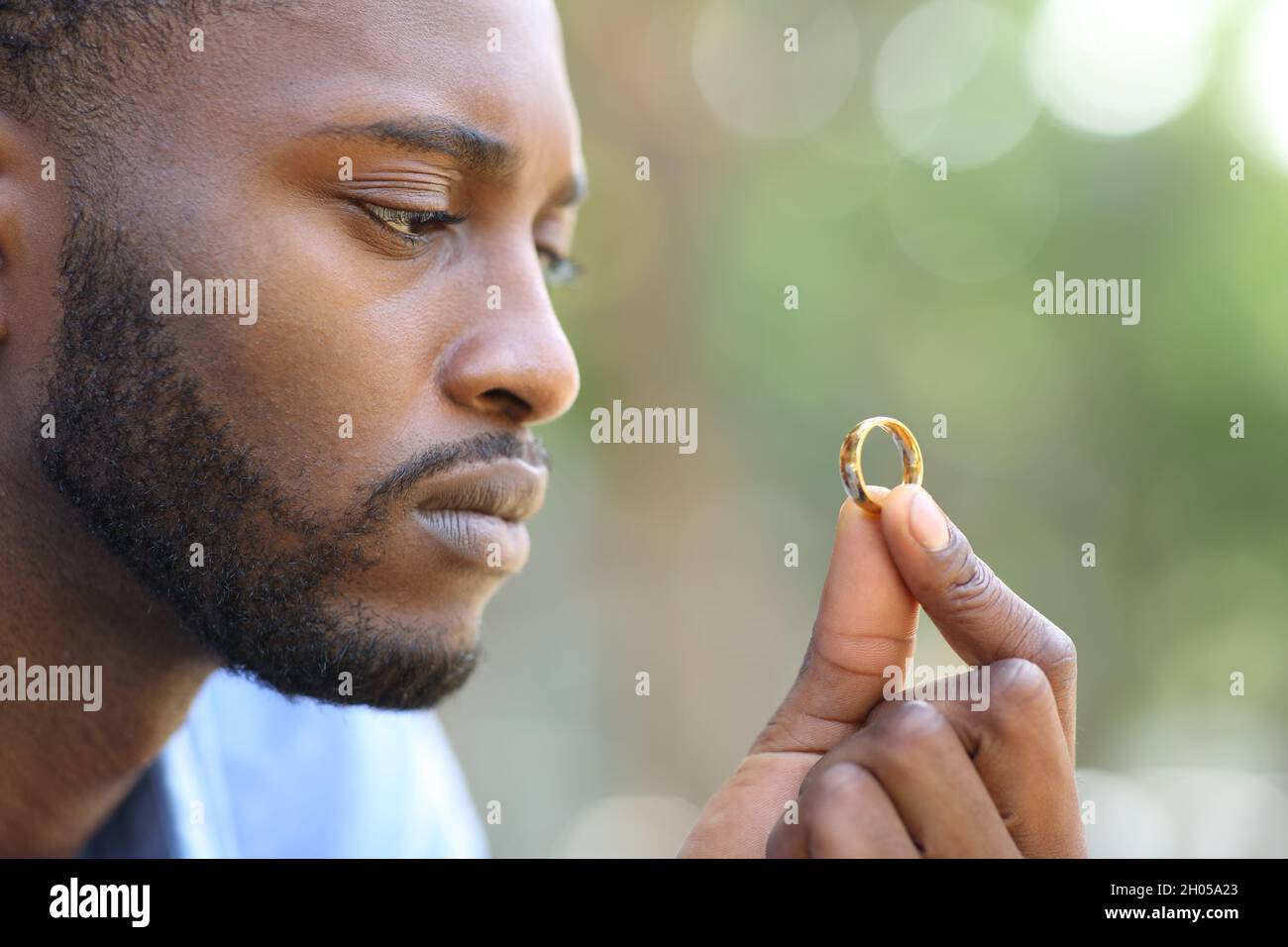 Trauriger schwarzer Ehemann zweifelt daran, einen Ehering in einem Park zu halten Stockfoto