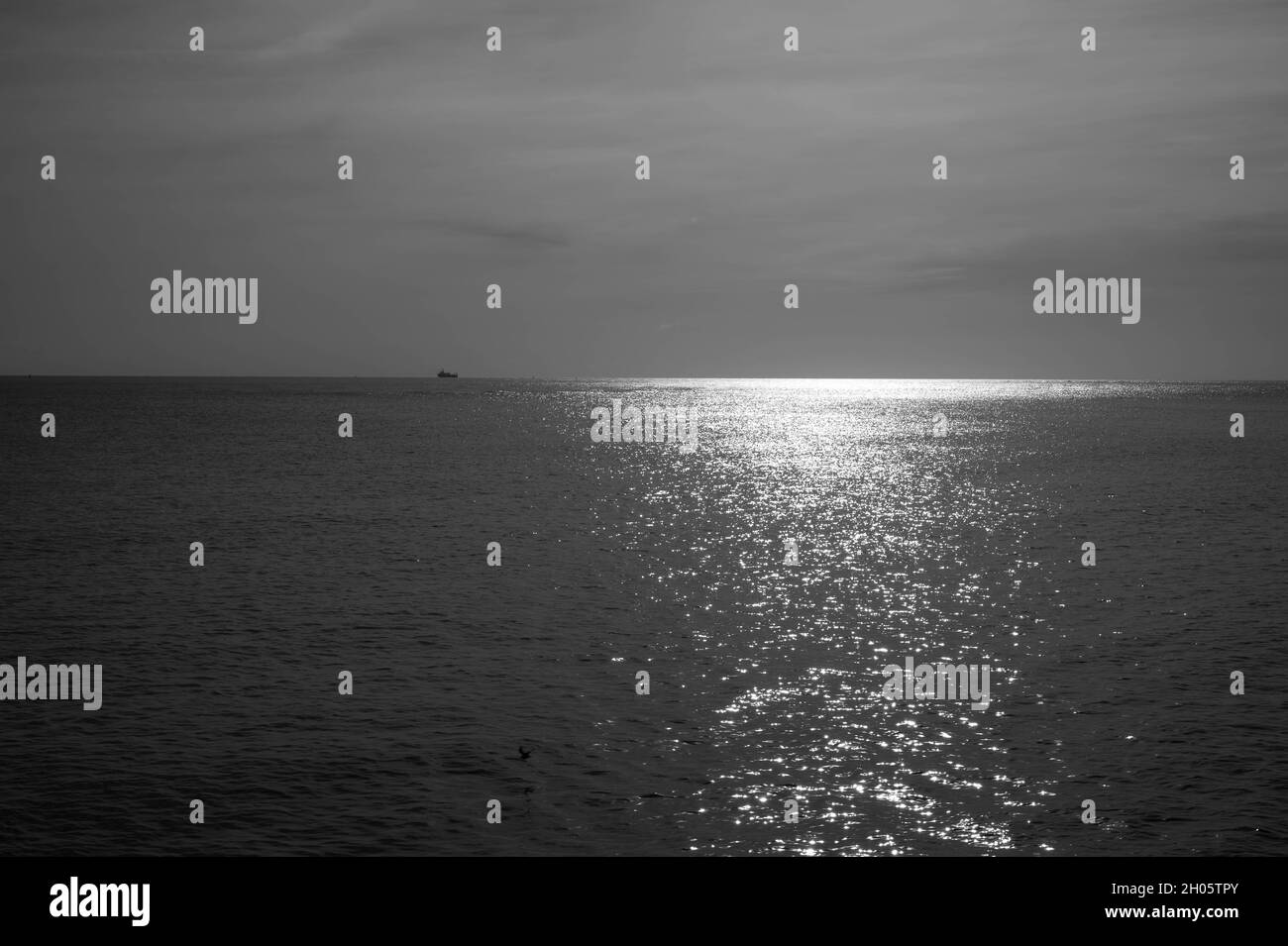 Heiteres Licht.die Sonne schimmert über dem Meer an der Ostküste englands mit einem Schiff am Horizont (monochrom) Stockfoto