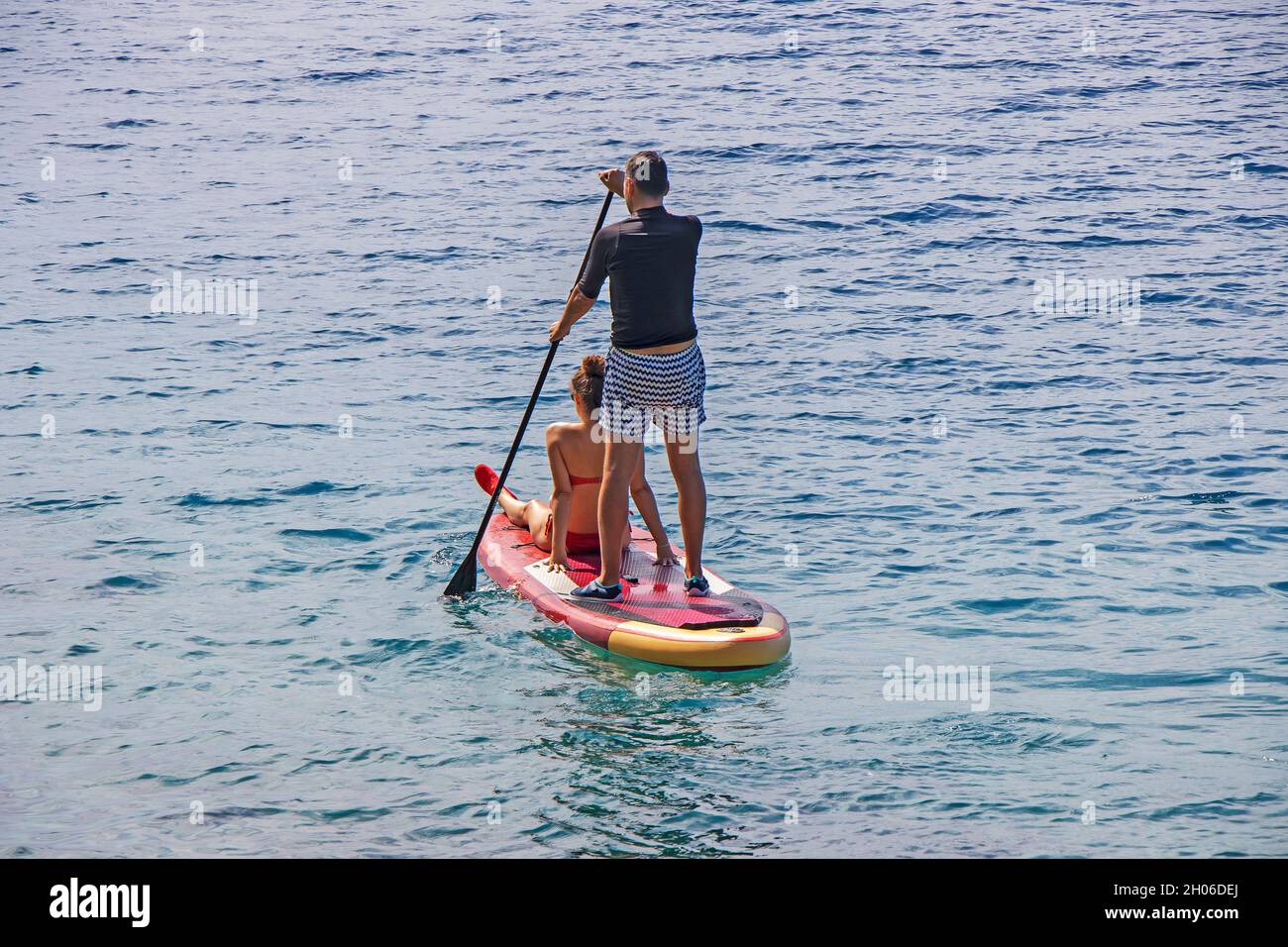 Junges Paar auf Stand Up Paddleboard Surfboard, das im Sommerurlaub gemeinsam surft Stockfoto