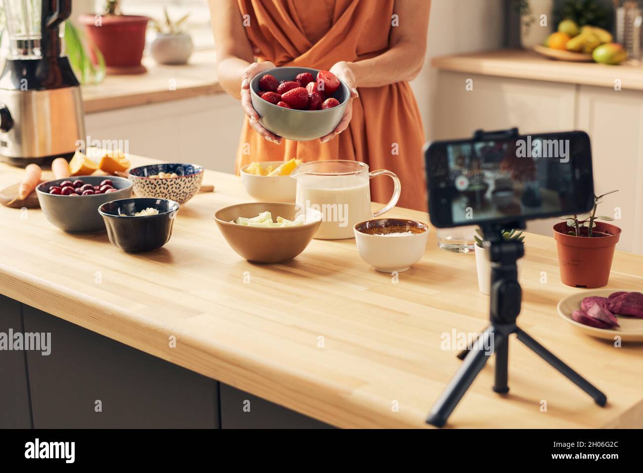 Junge Hausfrau mit Schale mit frischen Erdbeeren geben Meisterkurs des Kochens Smoothie Stockfoto