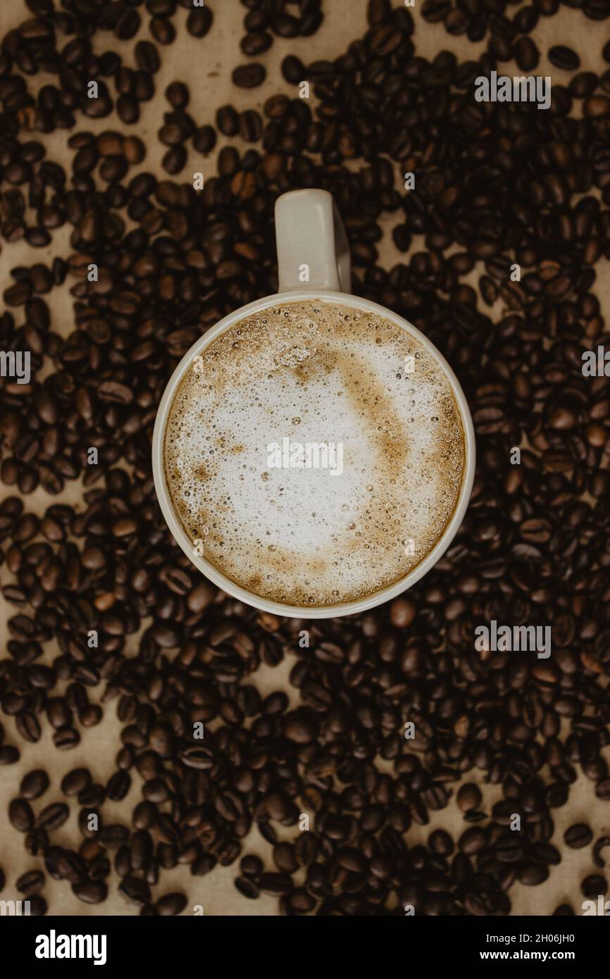 Stillleben einer Tasse Kaffee am Boden der Kaffeebohnen auf braunem Hintergrund. Stillleben-Kaffeefotografie. Stockfoto