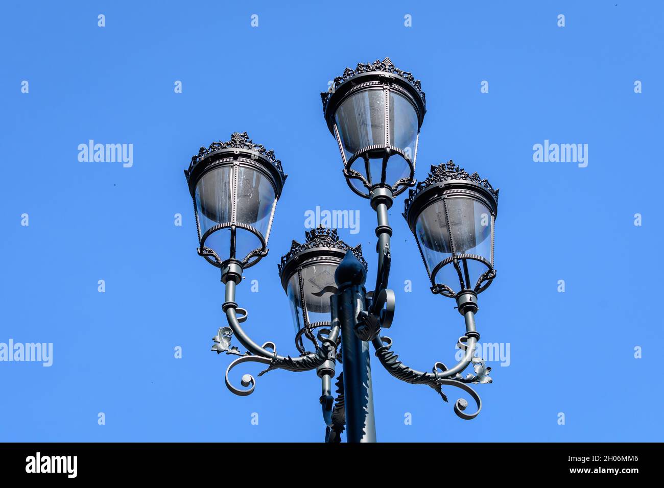 Vintage verrostete schwarze Lichtmast mit klarem blauen Himmel im Hintergrund in einer Straße im alten Stadtzentrum Stockfoto