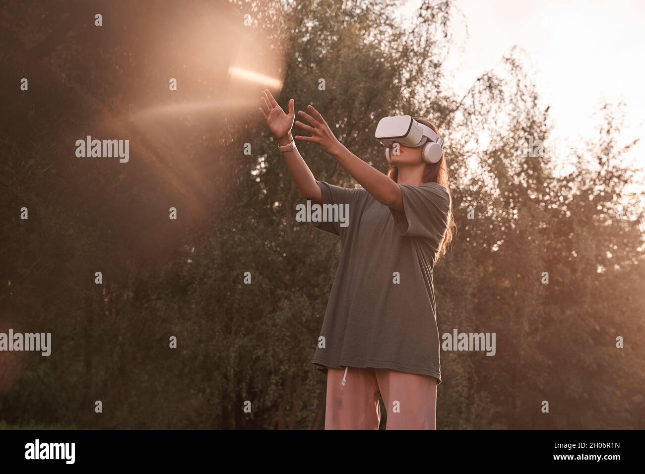 Ein Mädchen mit einer Virtual-Reality-Brille. Er reicht seine Hände an den Sonnenstrahl. Hochwertige Fotos Stockfoto