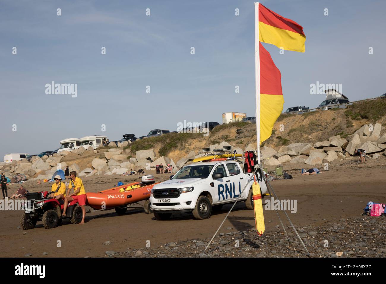 RNLI Rettungsschwimmer mit Fahrzeugen, Quad und aufblasbarem Lifer im Einsatz am Widemouth Surfing Beach Devon UK Stockfoto