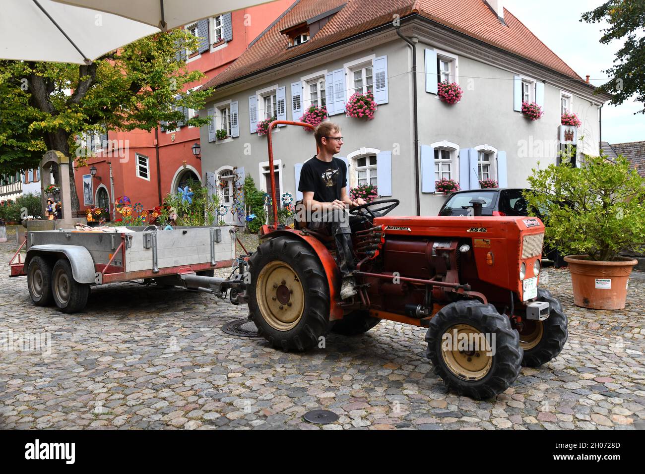 Junger deutscher Bauer fährt während der Weinlese mit einem kleinen Traktor durch das Dorf Burkheim Deutschland Stockfoto