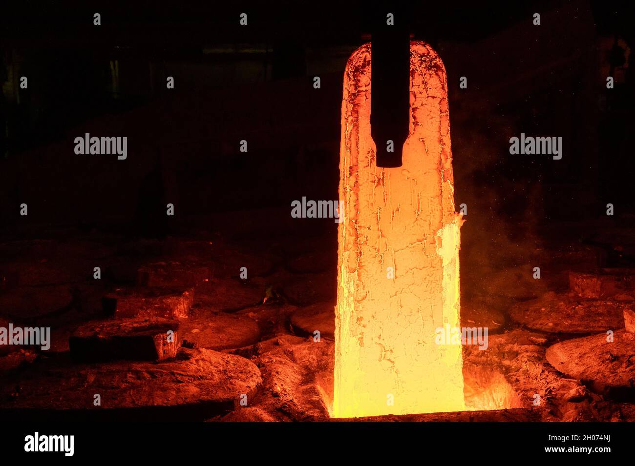 Der Greifer hebt ein großes, heißes Metallschmieden Stockfoto