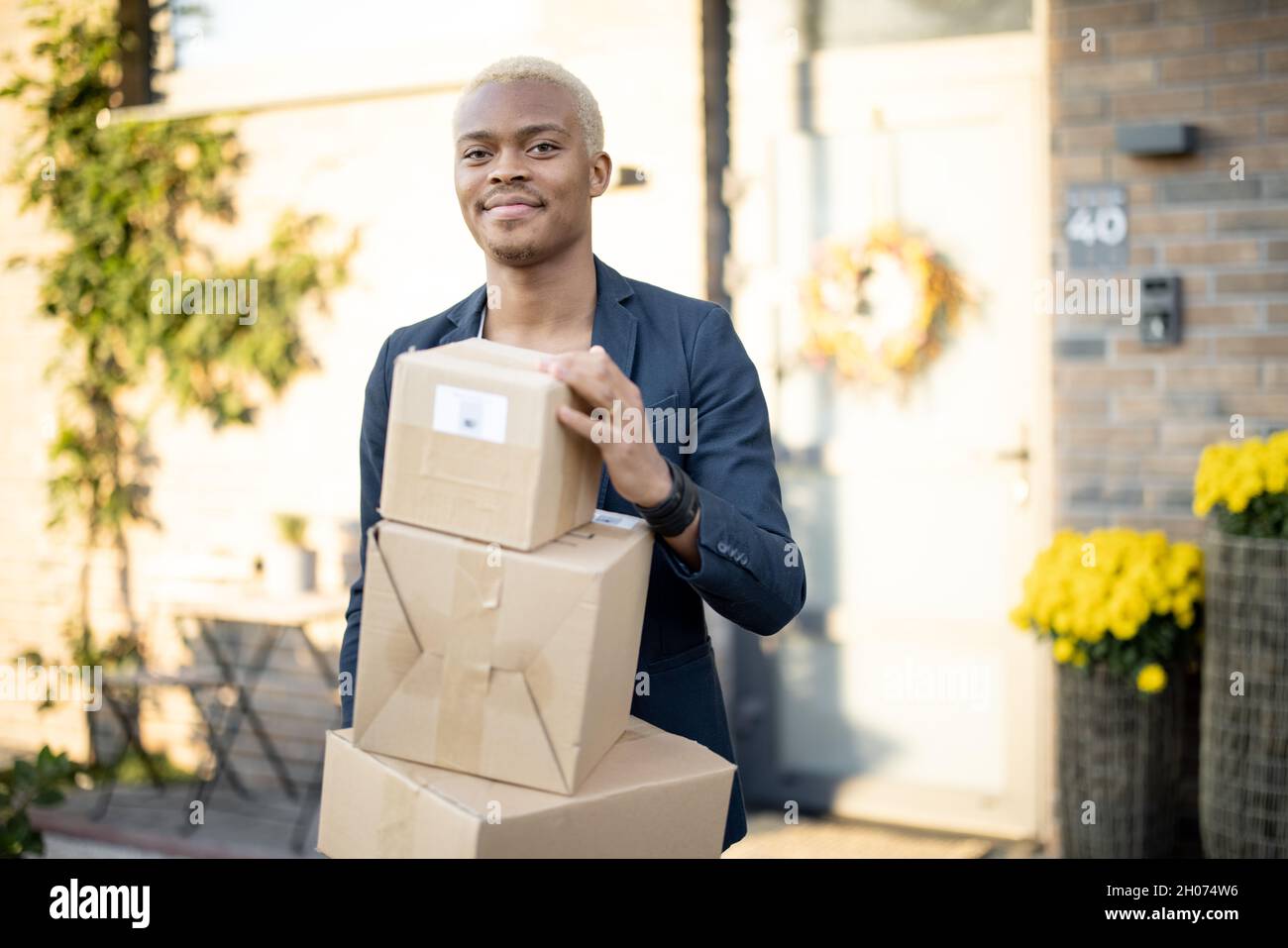 Lateinischer Mann, der mit Paketen in der Nähe seines Hauses steht Stockfoto