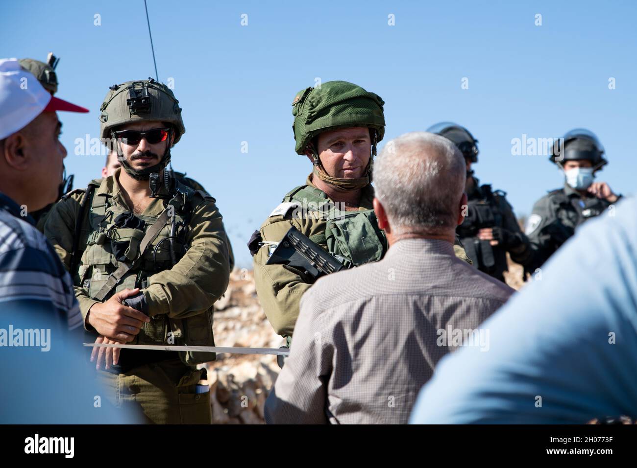 Israel Defence forces Soldaten verhindern den Zugang von Einheimischen und Aktivisten von Olivenplantagen während der Erntezeit. Die Plantage am Stadtrand von Salfit wurde im letzten Jahr an einen neuen jüdischen Vorposten angeschlossen - „AVI view Farm“, obwohl die Plestinier Landtaten für das Land besitzen. Während eines Versuchs, die weiße Linie zu durchbrechen, die eine geschlossene Militärzone in den Plantagen einschließt, verwendete die Armee Betäubungsgranaten und verhaftete drei Aktivisten. Salfit, das Westjordanland, am 11. Oktober 2021. (Matan Golan/Alamy Live News) Stockfoto