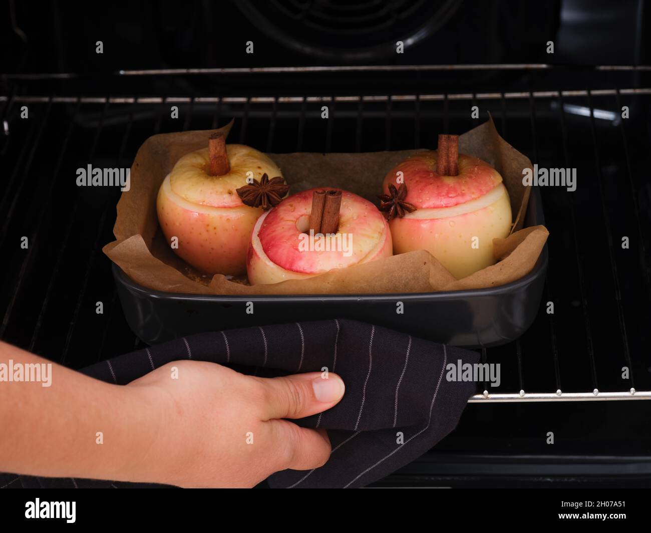 Frau, die aus dem Ofen gebackene Äpfel mit Zimt und Sternanise in sich nahm. Nahaufnahme. Stockfoto