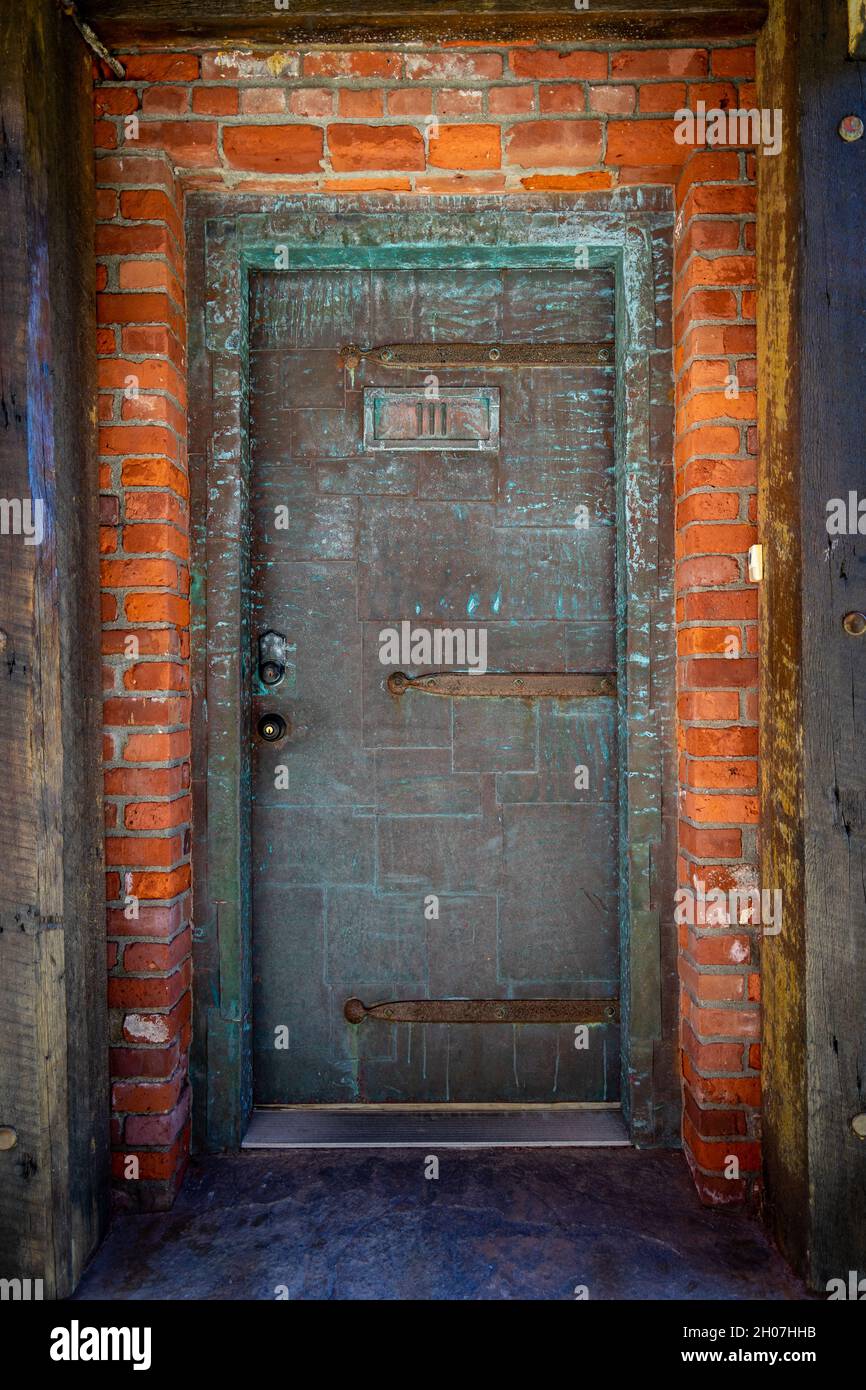 Schwere Kupfertür mit grünem Oxidationseingang zum alten Ziegelgebäude gut für den Hintergrund Stockfoto