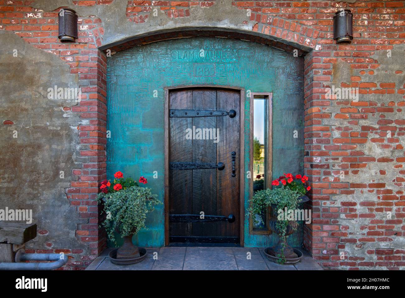 Port Townsend, WA. USA -09/29/2020: Waterfront Clam Cannery Brick Building Eingang enthält alte Holztür und oxidiertes grünes Kupfer Stockfoto