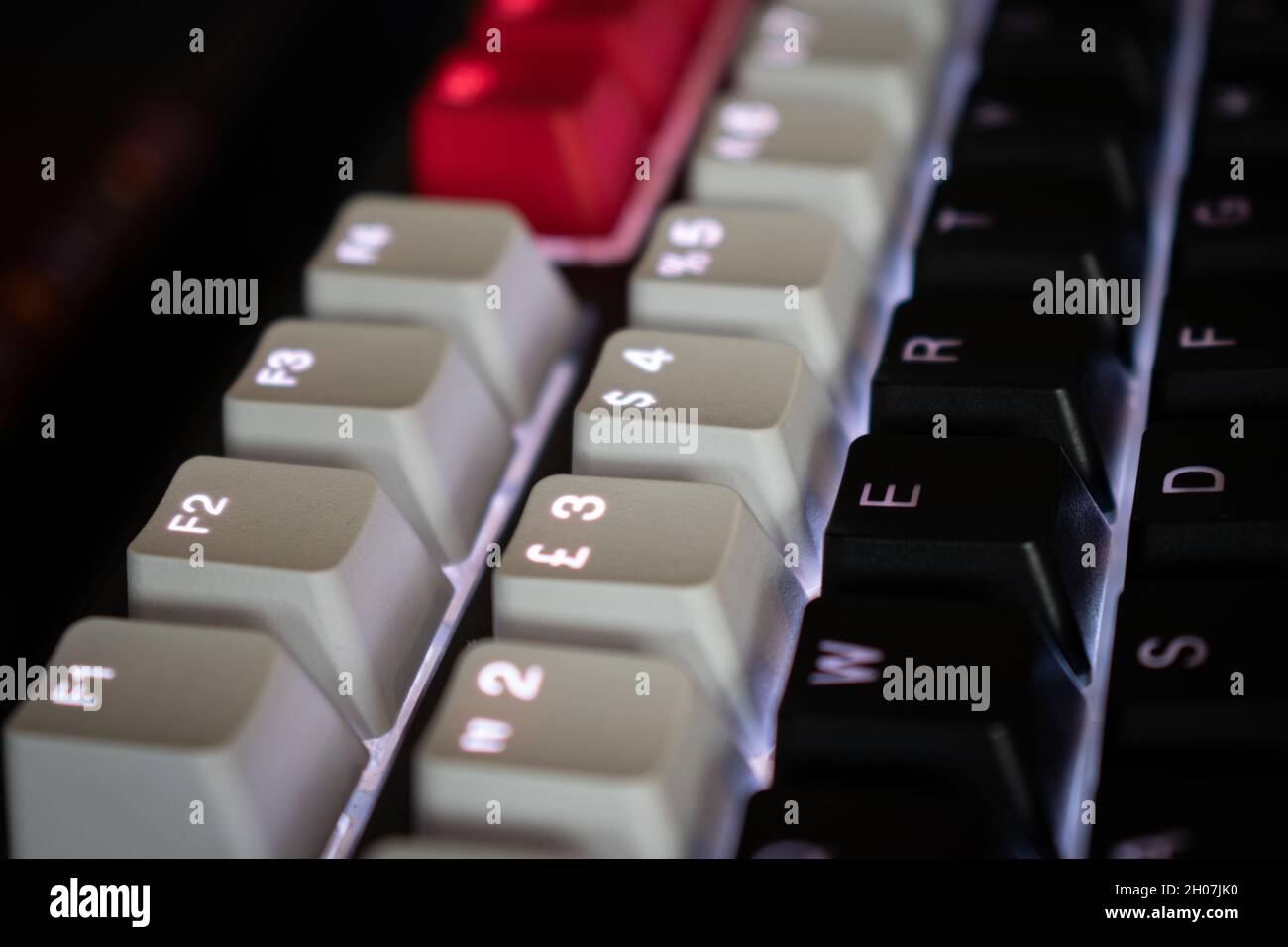 Weiße, hintergrundbeleuchtete mechanische Tastatur mit schwarzen, weißen und roten Tastenkappen in einem Winkel Stockfoto