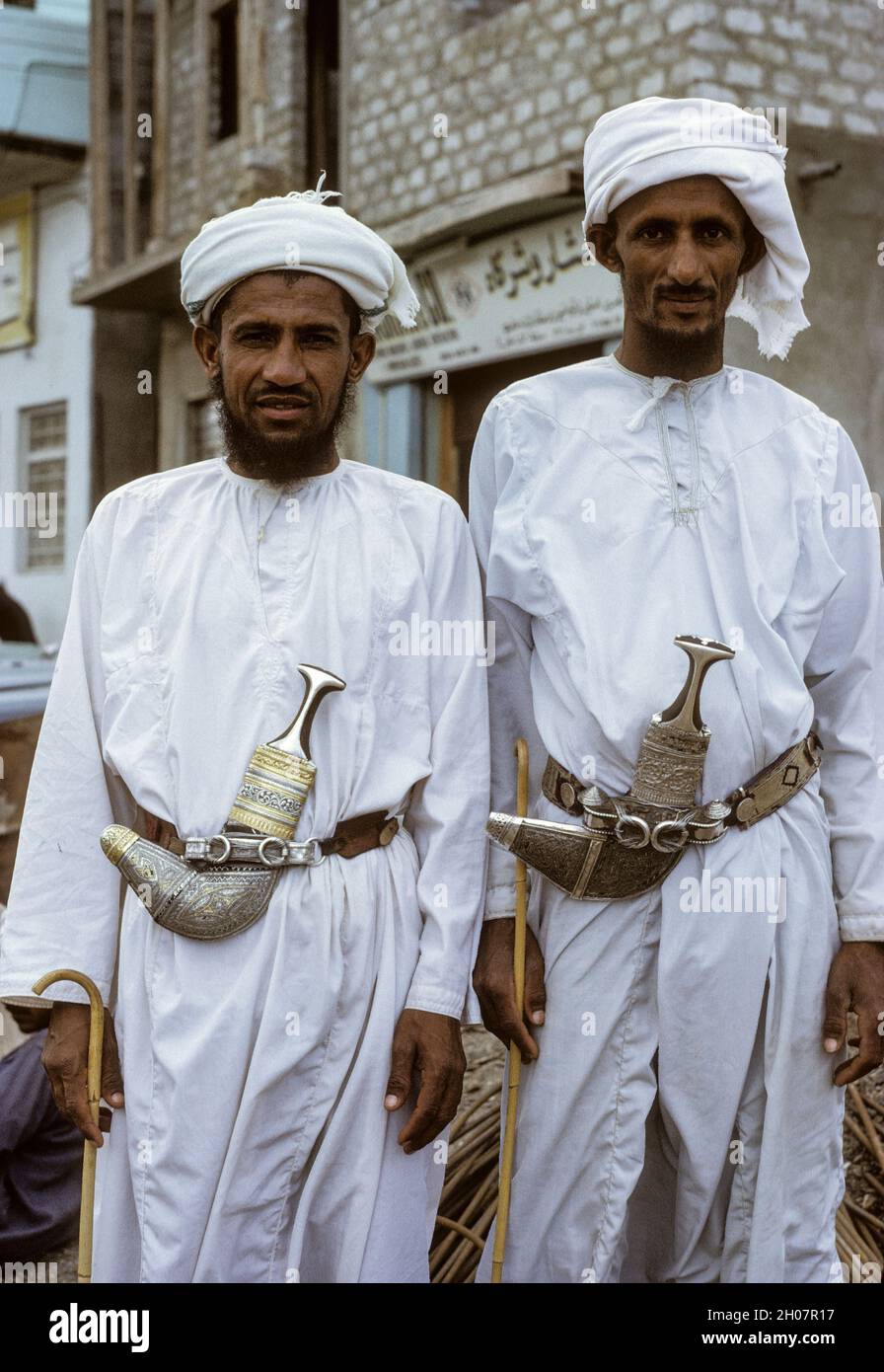Oman, März 1972.  Zwei omanischen Männer.  Jeder trägt eine Dishdasha (weißes Gewand), ein Khanjar (gebogene Dolch), eine Msarr oder Massar (Leiter Turban), und ein Asa oder Khuzran (traditionelle Spazierstock). Stockfoto