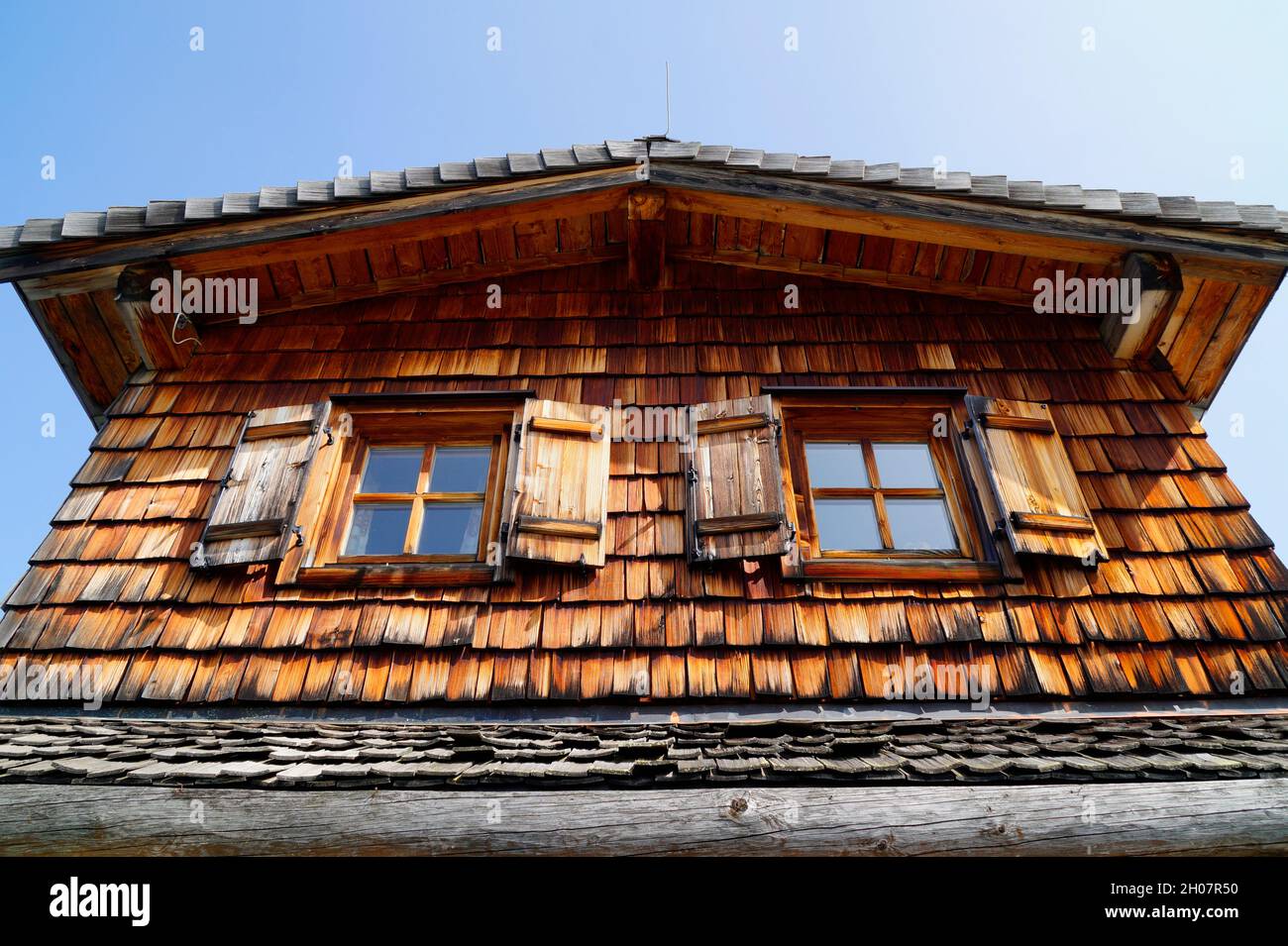 Ein Fenster mit hölzernen Fensterläden einer rustikalen Holzhütte in den österreichischen Alpen der Region Schladming-Dachstein (Österreich) Stockfoto