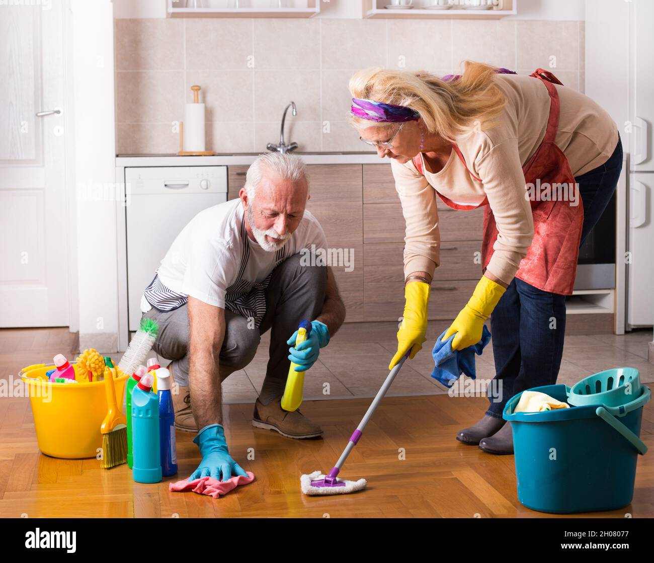 Glückliches Seniorenpaar, das gemeinsam am Boden Aufgaben erledigt Stockfoto