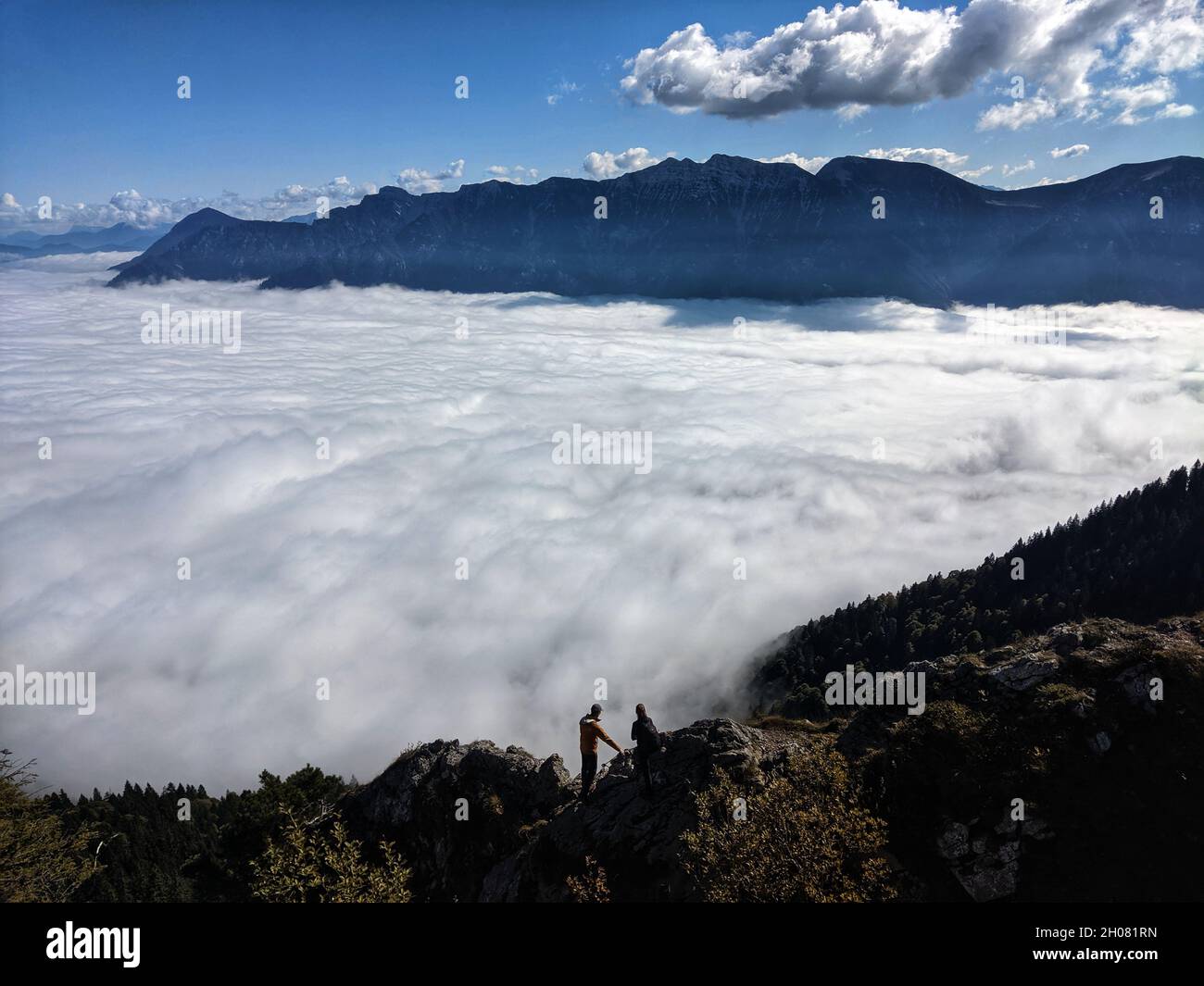 Ettal Oberammergau, Bayern, Deutschland. Oktober 2021. Zwei Wanderer-Kletterer am Gipfel des Ettal Manndl in Oberammergau, Bayern, schauen auf die Wolken, die das Tal unter ihnen füllen. (Bild: © Sachelle Babbar/ZUMA Press Wire) Stockfoto
