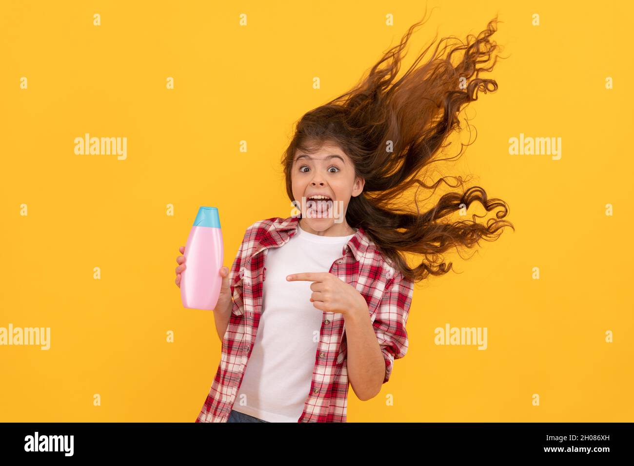 Happy teen Mädchen mit langen lockigen Haaren halten Shampoo-Flasche, Keratin Stockfoto