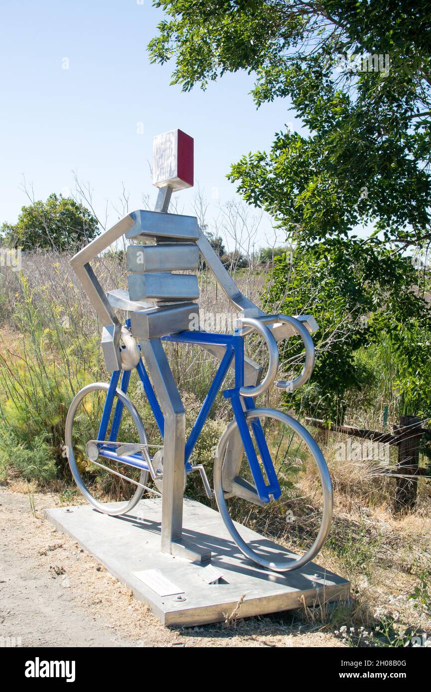Edelstahlskulptur von James Mehr: Ein Radfahrer auf einem blauen Rennrad blickt mit einem Fuß auf den Horizont in Widmung von Bill Bliss Stockfoto