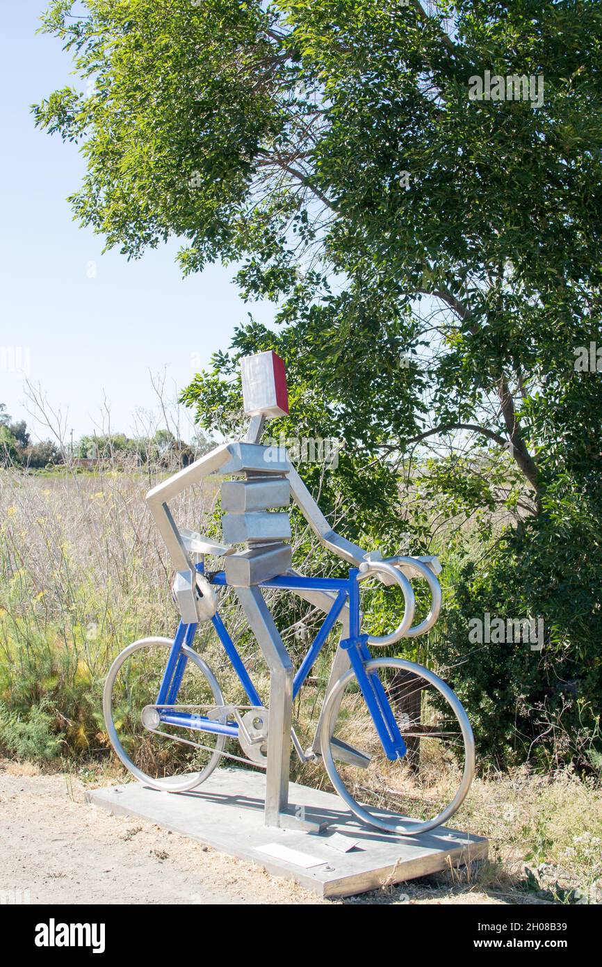 Edelstahlskulptur von James Mehr: Ein Radfahrer auf einem blauen Rennrad blickt mit einem Fuß auf den Horizont in Widmung von Bill Bliss Stockfoto