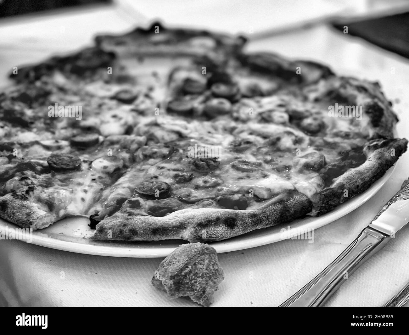Graustufen-Schuss einer ganzen leckeren Pepperoni-Pizza Stockfoto