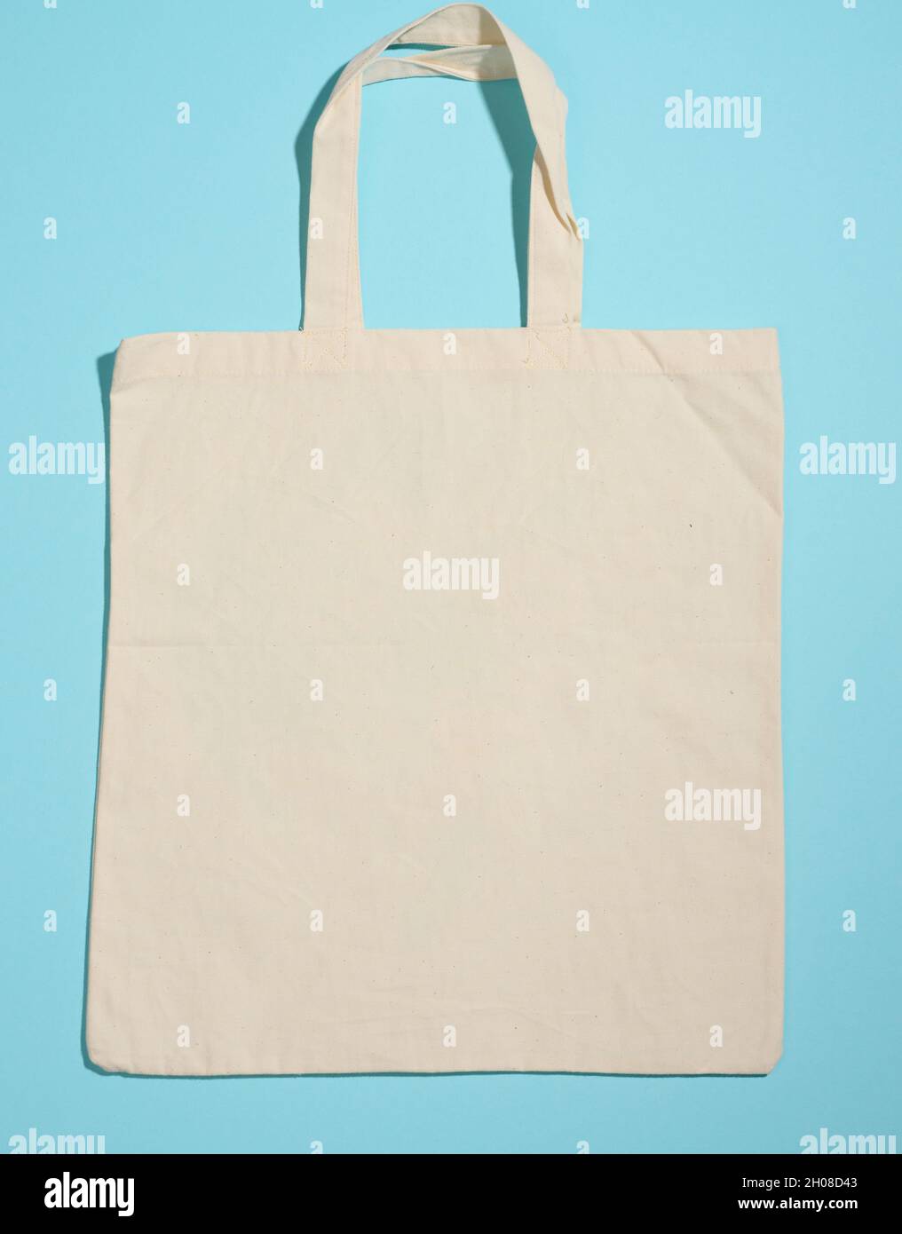 Leeres Leinen umweltfreundliche beige Leinwand-Tragetasche für Branding auf blauem Hintergrund. Durchsichtige wiederverwendbare Tasche für Lebensmittel, Nachbau. Flach liegend Stockfoto