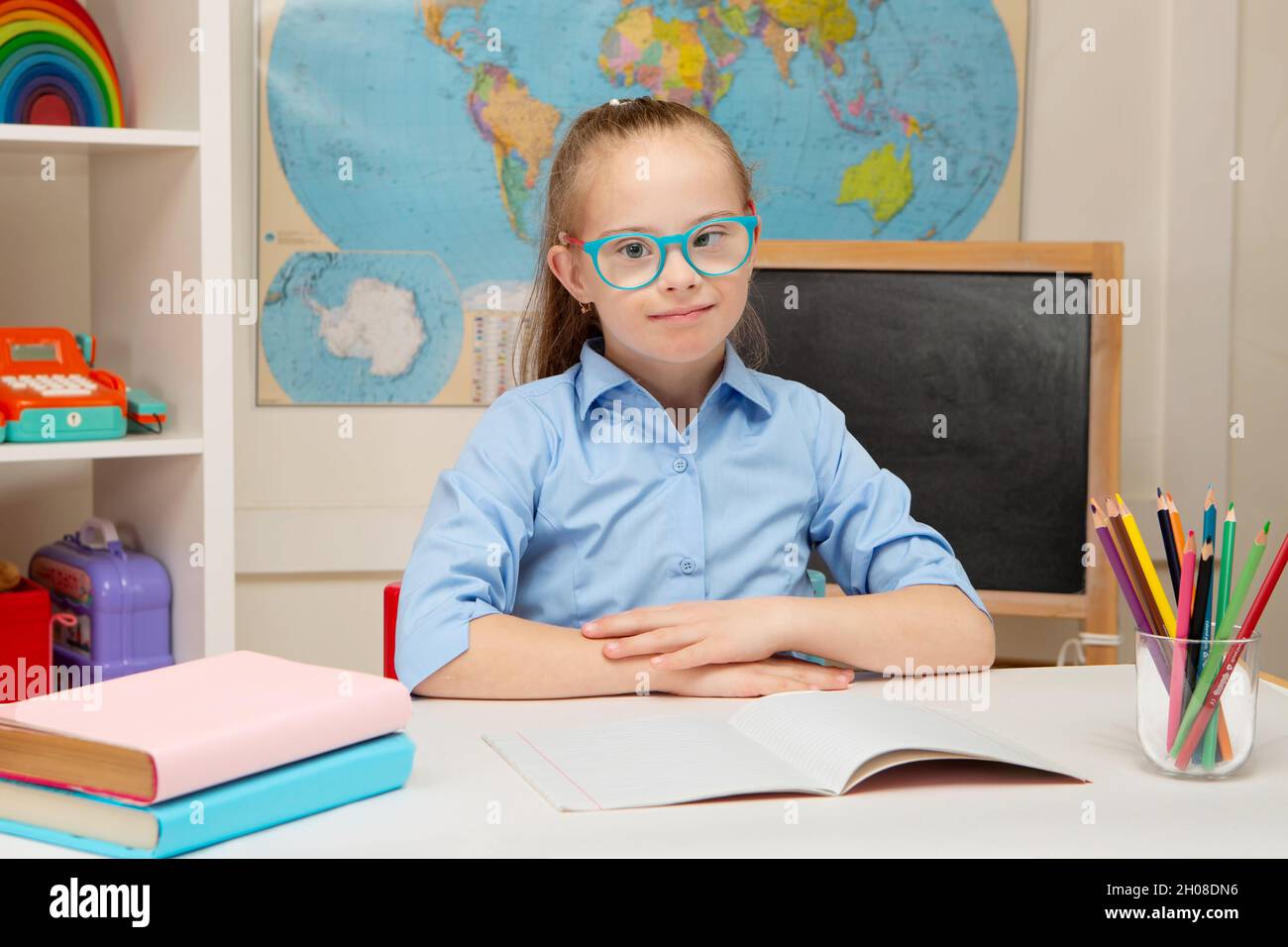 Ein schönes Mädchen mit Down-Syndrom sitzt an Deck in der Schule Stockfoto