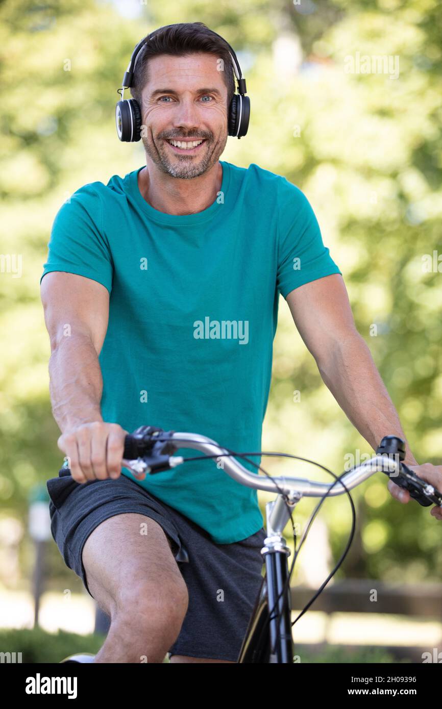 Mann, der mit Kopfhörern mit dem Fahrrad durch die Stadt fährt Stockfoto