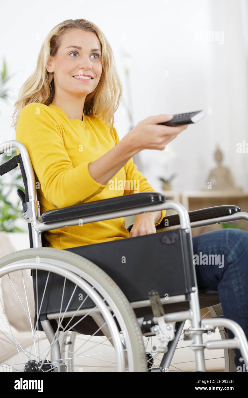 Frau im Rollstuhl wechselt das fernsehprogramm Stockfoto