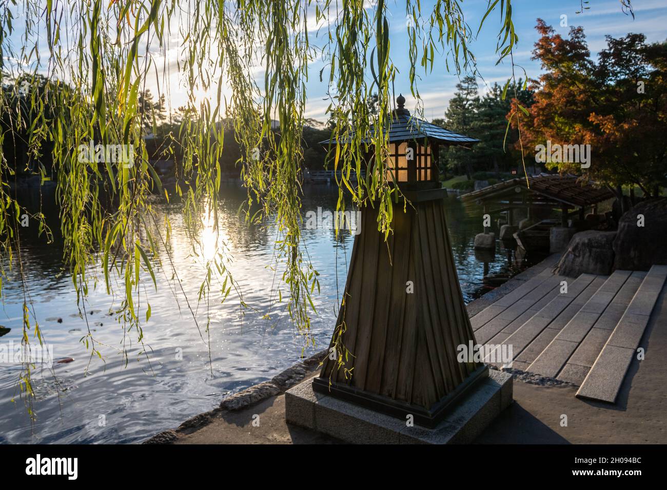 Steindeck und japanische Holzlaterne am Teich im Tokugawa-Garten. Stockfoto