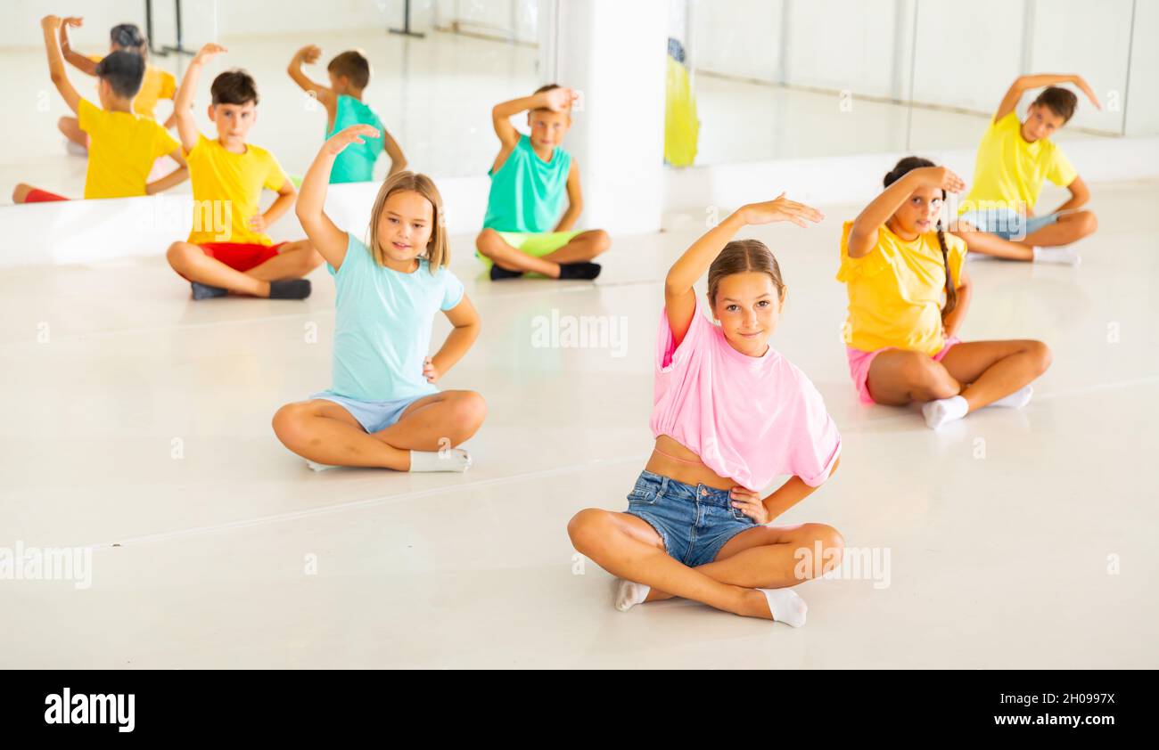 Gruppe von Kindern, die während des Yoga-Kurses im Fitnesscenter trainieren - vakrasana Pose Stockfoto