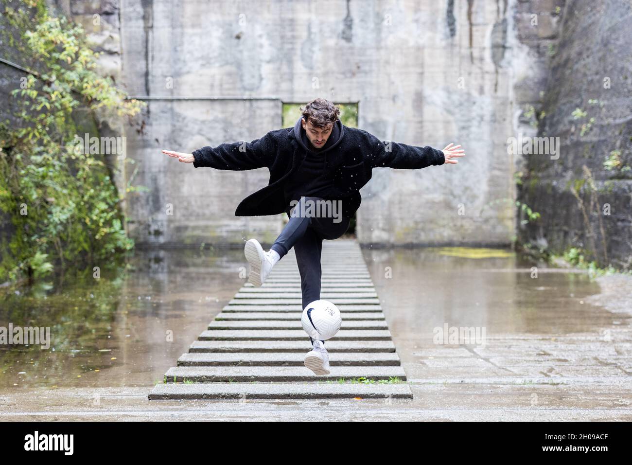 Duisburg, Deutschland. Oktober 2021. Marcel Gurk, zweimaliger deutscher Freestyle-Champion, präsentiert einen Trick mit einem Ball in einem alten industriellen Setting. Spektakuläre Fußballtricks auf TikTok, Familienalltag auf YouTube oder Geschichten aus dem Nebenjob auf Instagram – immer mehr Fußballer und auch Schiedsrichter aus den Klassen unterhalb der 3. Liga präsentieren sich und ihr Leben in den sozialen Netzwerken. Quelle: Marcel Kusch/dpa/Alamy Live News Stockfoto