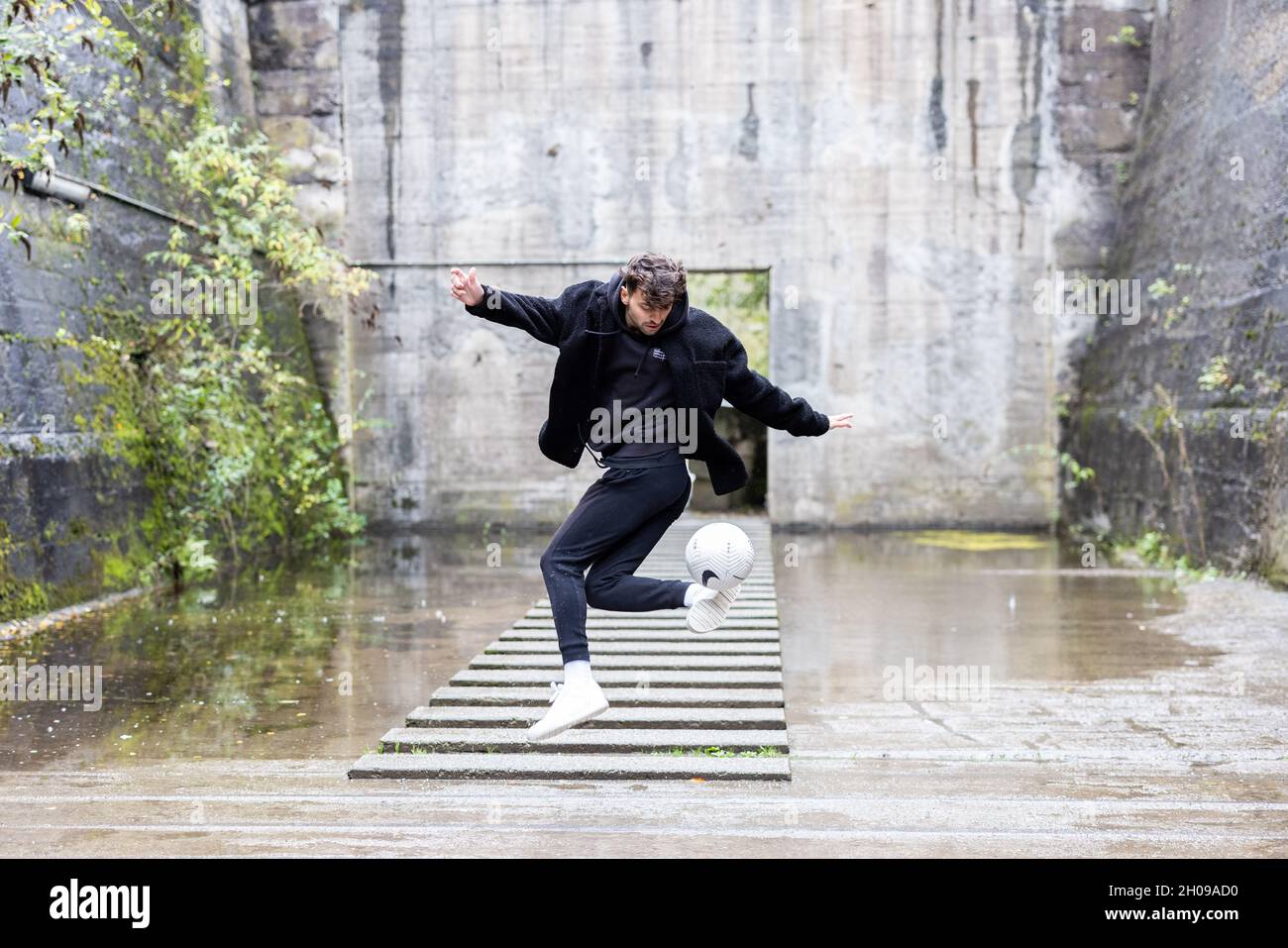Duisburg, Deutschland. Oktober 2021. Marcel Gurk, zweimaliger deutscher Freestyle-Champion, präsentiert einen Trick mit einem Ball in einem alten industriellen Setting. Spektakuläre Fußballtricks auf TikTok, Familienalltag auf YouTube oder Geschichten aus dem Nebenjob auf Instagram – immer mehr Fußballer und auch Schiedsrichter aus den Klassen unterhalb der 3. Liga präsentieren sich und ihr Leben in den sozialen Netzwerken. Quelle: Marcel Kusch/dpa/Alamy Live News Stockfoto