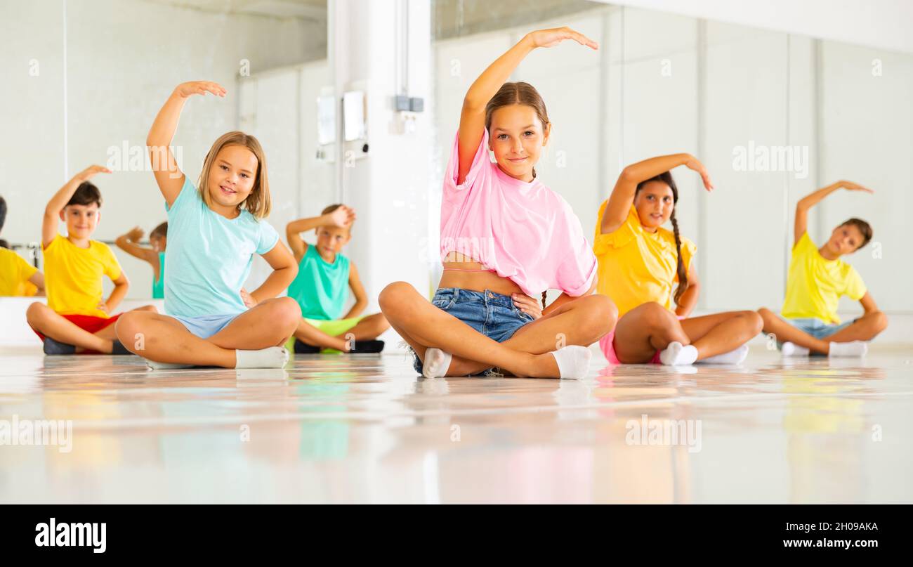 Gruppe emotionaler Kinder, die im Tanzstudio Yoga machen Stockfoto