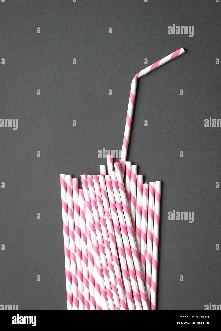 Glasform mit Stroh aus Papierhalmen auf schwarzem Hintergrund. Party oder kein Plastikkonzept. Stockfoto