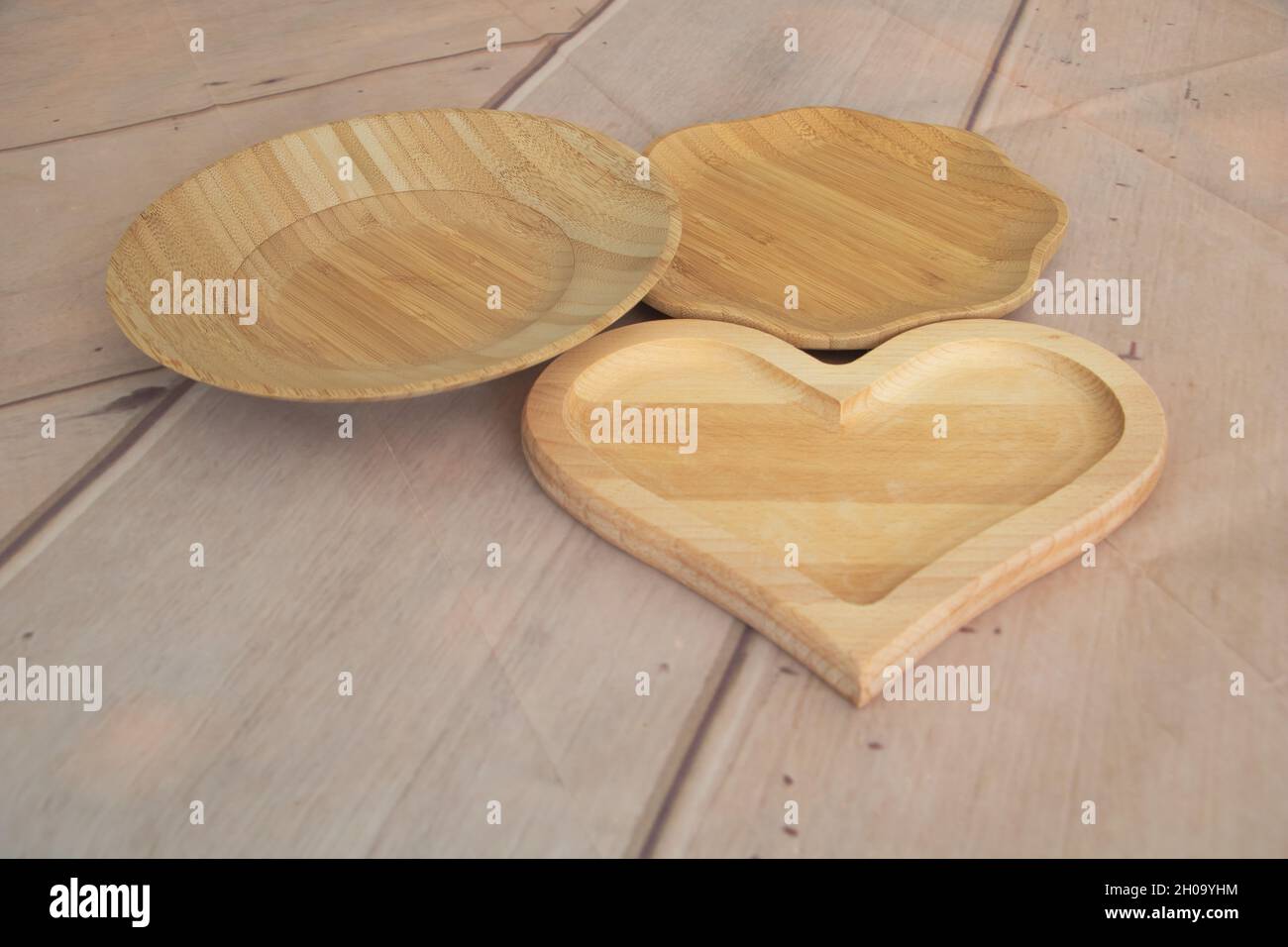 Zwei Bambusplatten aus biologischem Anbau und ein herzförmiger Holzteller Stockfoto