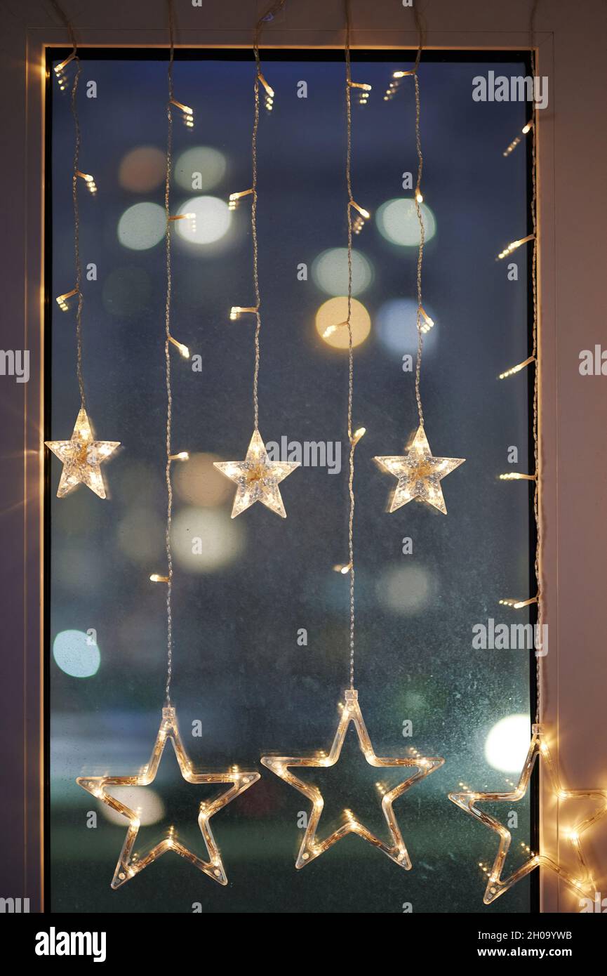 Verzierte Fenster mit weihnachtslichtern auf verschwommenem Abendhintergrund Stockfoto