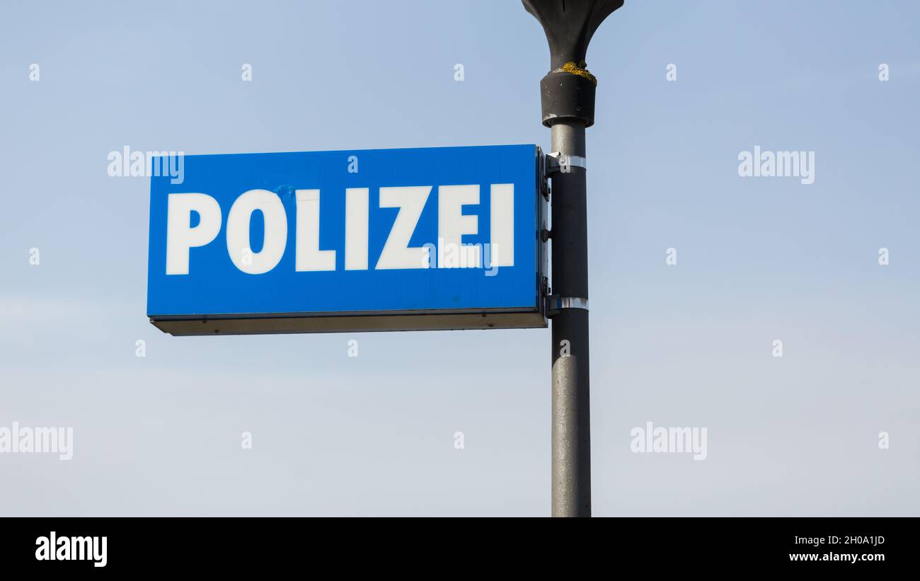 Oberammergau, Deutschland - 26. Feb 2021: Polizei-Schild an einer Laterne - vor der Polizeiwache Oberammergau. Blauer Himmel Hintergrund. Stockfoto