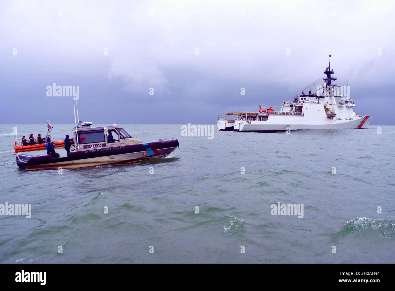 Am 9. Januar 2021 patrouillieren kleine Boote der US-Küstenwache und der Guyana-Küstenwache hinter dem USCGC Stone (WMSL 758) vor der Küste Guyanas. Die beiden Länder haben am 18. September 2020 ein bilaterales Abkommen zur Zusammenarbeit bei der Unterdrückung illegaler maritimer Aktivitäten in den Gewässern Guyanas geschlossen. Stockfoto