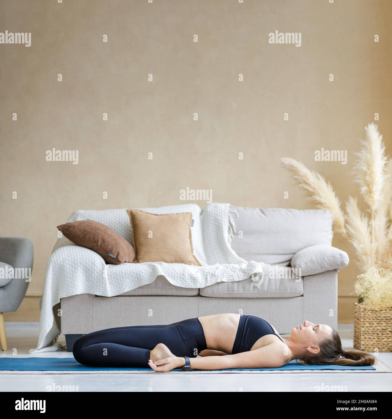 Junge sportliche Frau macht morgens Yoga zu Hause üben. Stockfoto