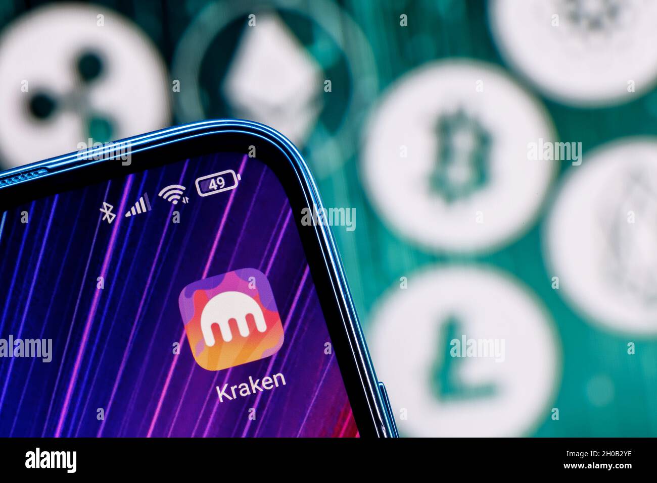 Kraken ist eine Kryptowährungsbörse. Kraken App auf dem Smartphone-Bildschirm vor dem Hintergrund der wichtigsten Kryptowährungen. Stockfoto