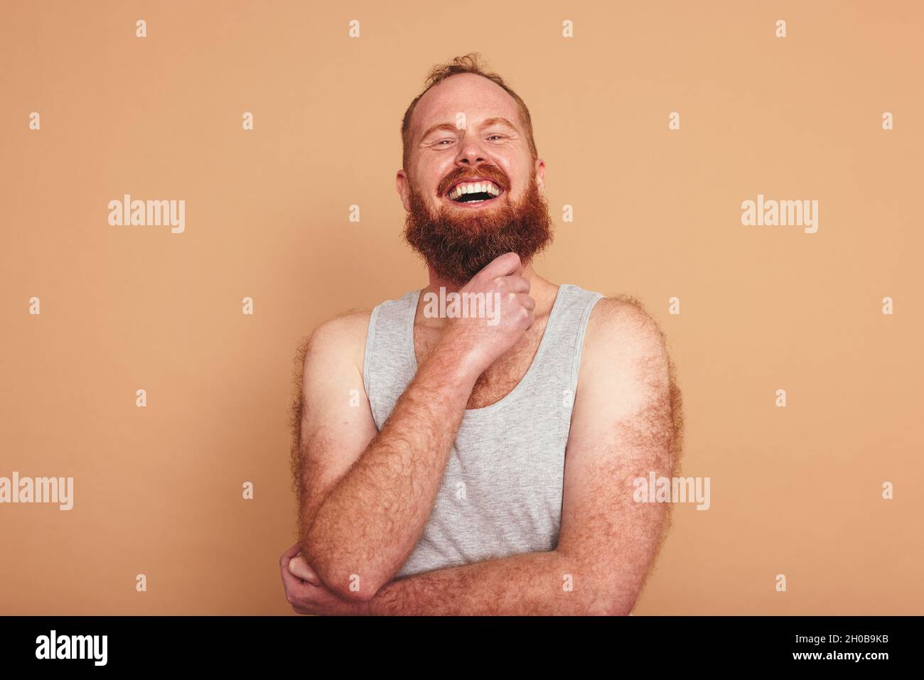 Fröhlicher Mann, der in einem Studio die Kamera anlächelt. Body positive junge Mann vor einem Studio Hintergrund stehen. Selbstbewusster junger Mann, der sich wohlfühlt Stockfoto