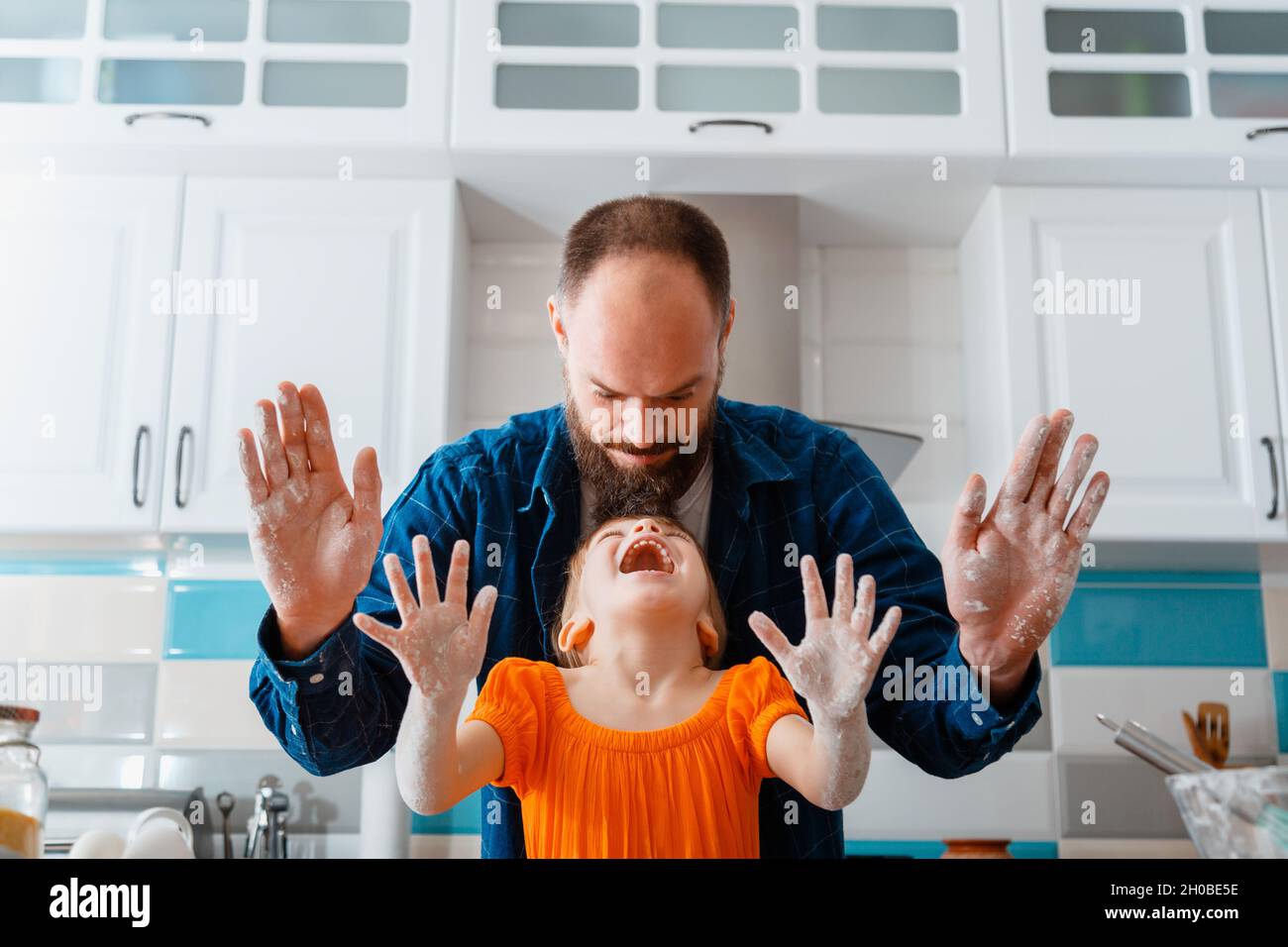 Kleines Mädchen haben Spaß spielen mit Papa beim Kochen Backen in der Küche. Tochter und kaukasischer Vater zeigen nach dem Teig die Hände schmutzig, lachen viel Spaß Stockfoto