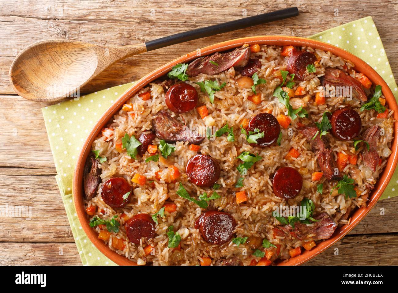 Portugiesischer Entenreis arroz de pato gekocht mit Rotwein, Zwiebeln, Karotte und Chorizo in der Backform auf dem Holztisch. Horizontal oben Vie Stockfoto