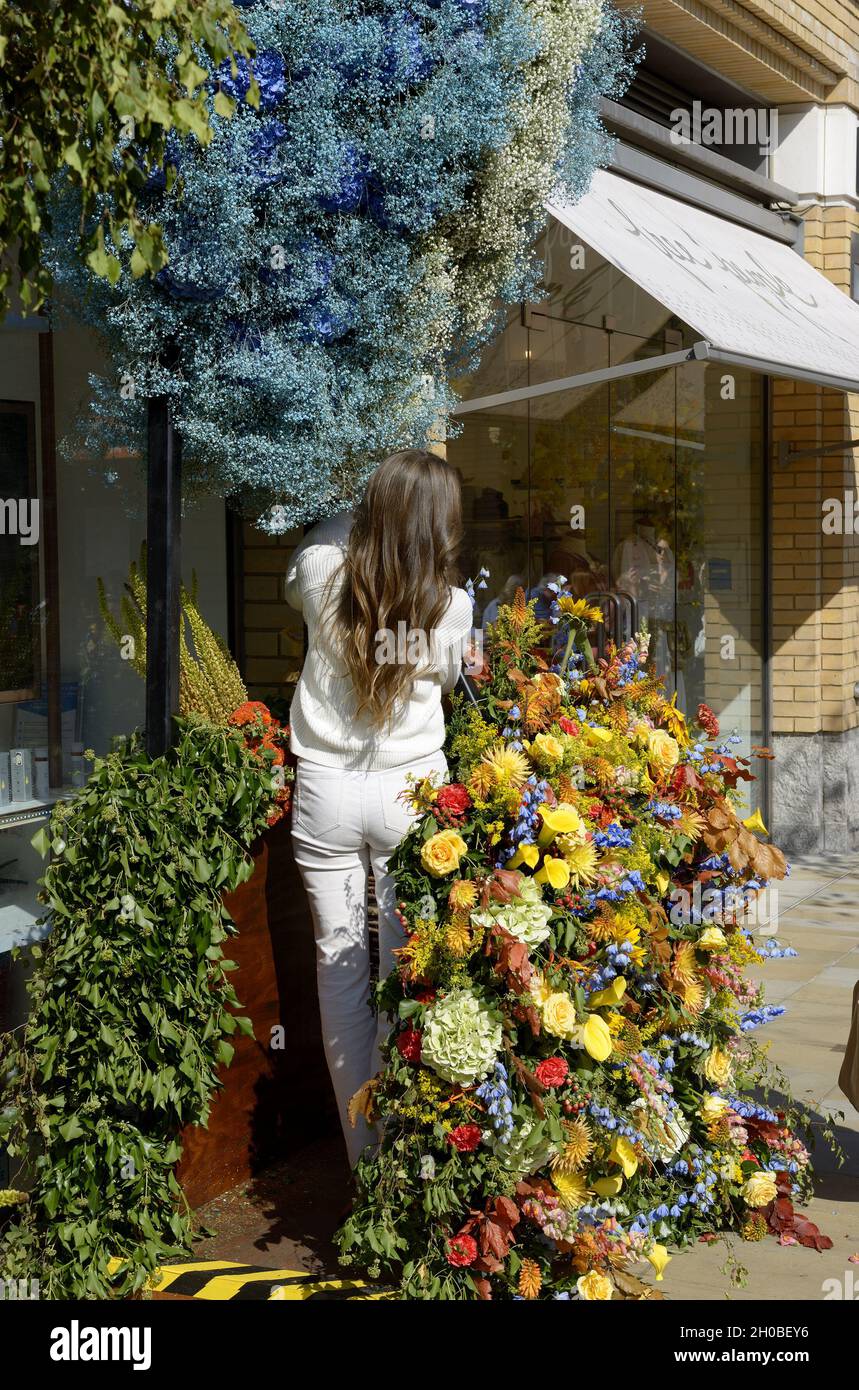 Junge Frau, die während der jährlichen Blumenkunstausstellung in Chelsea in Bloom und der Blumendusche in den Geschäften und Straßen von Chelsea eine Blumenausstellung anpasst Stockfoto